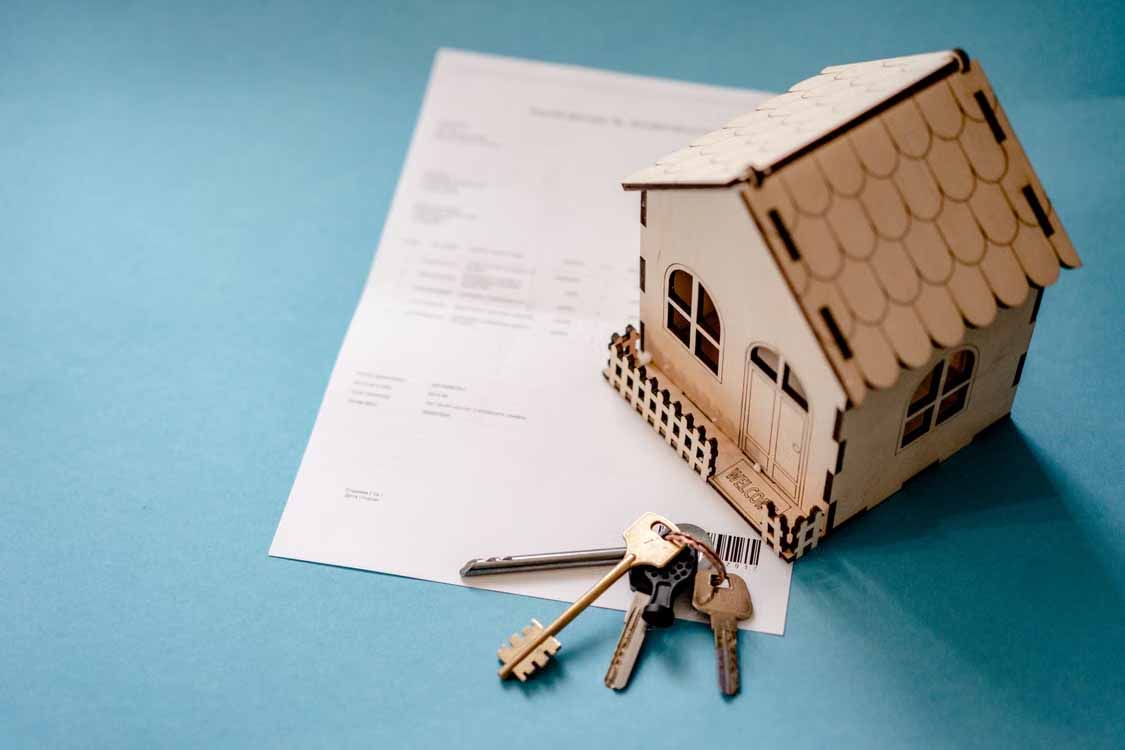 Model house and keys resting on mortgage paperwork, representing refinancing, switching banks, and mortgage cashback offers in New Zealand.